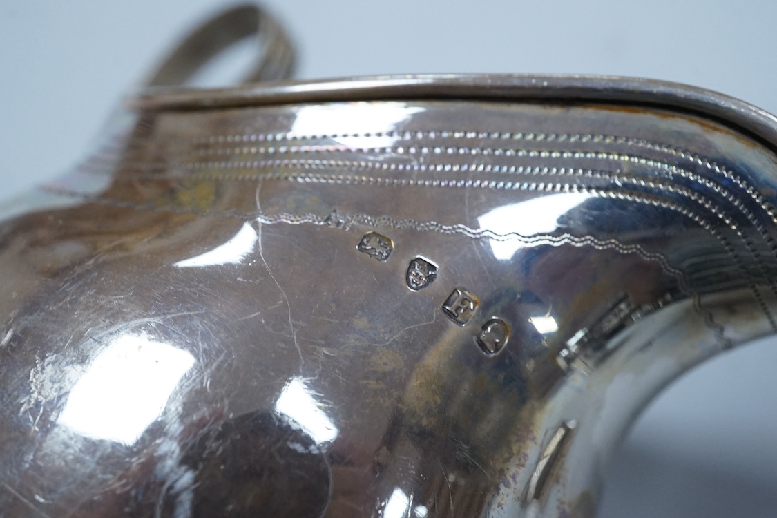 A George III silver cream jug, of oval form, London, 1801, 11cm, a George III silver helmet shaped cream jug, London, 1793, a George III small silver sugar pail, London, 1799 and a George V silver 'whisky' label, 8.4oz.